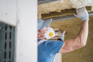 House Insulating by Caucasian Worker. Home Roof Remodeling.